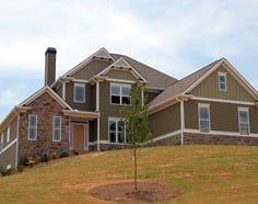 A large house is sitting on top of a grassy hill.