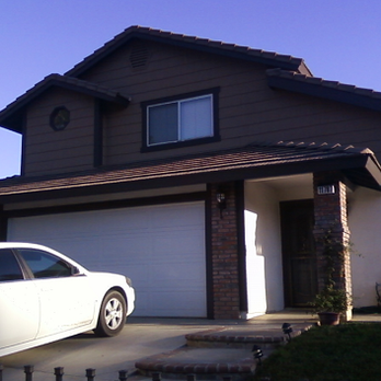 A white car is parked in front of a house with the number 1318 on it