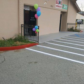 A bunch of balloons are hanging from a fence in front of a building.