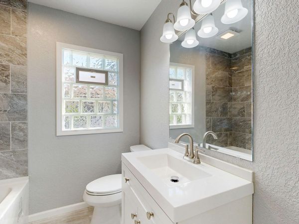 Modern bathroom with double-sink vanity, large mirror, window, and tiled shower area