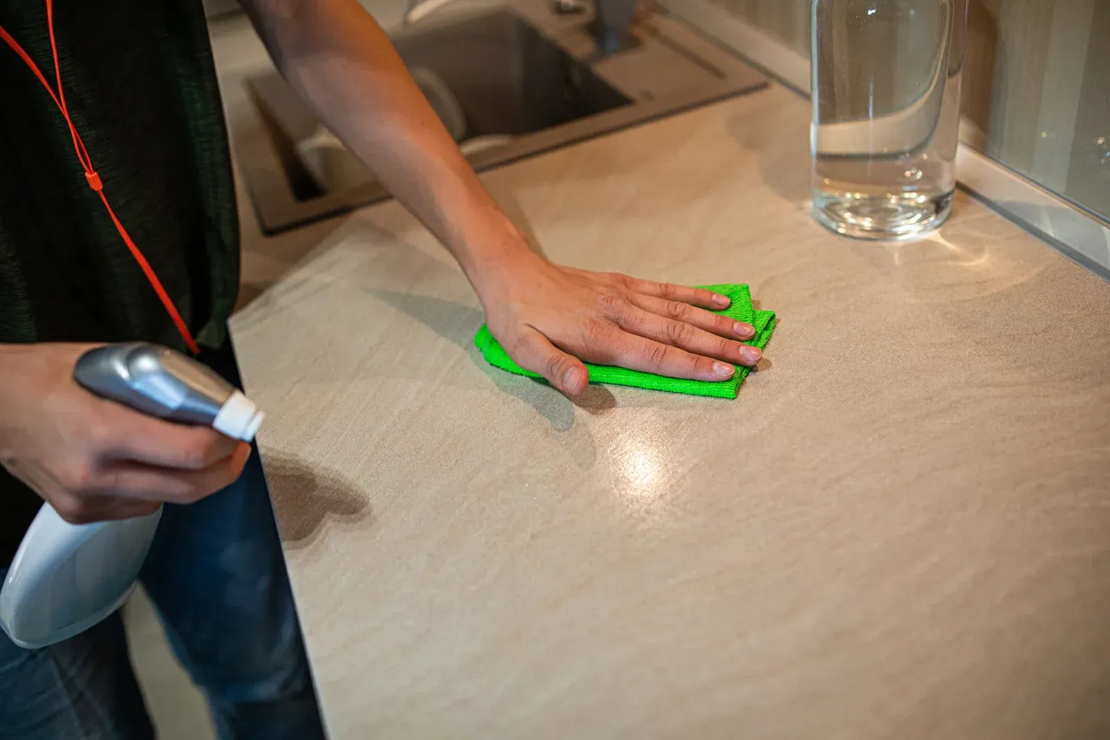 A person is cleaning a kitchen counter with a green cloth.