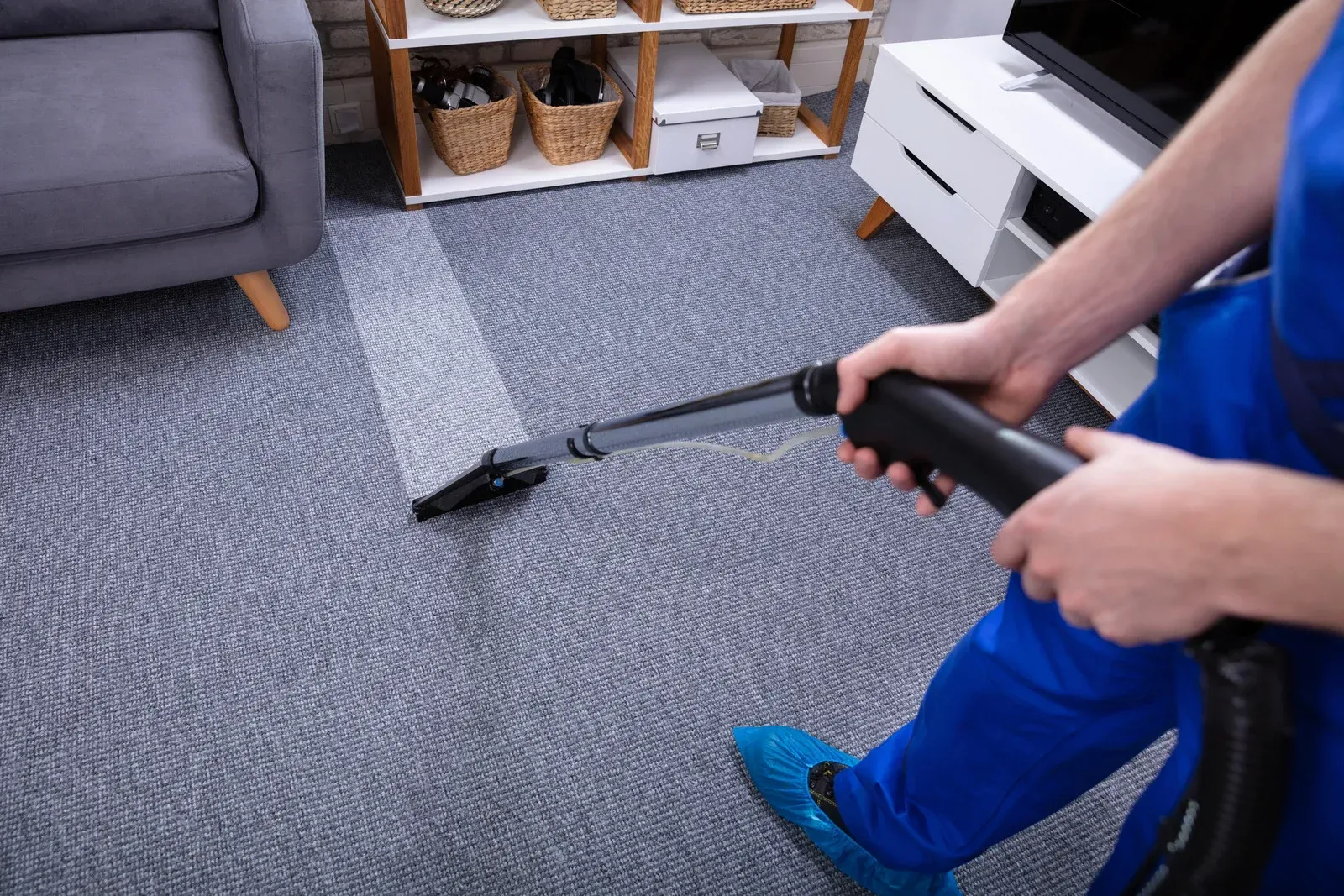 A person is cleaning a carpet with a vacuum cleaner in a living room.