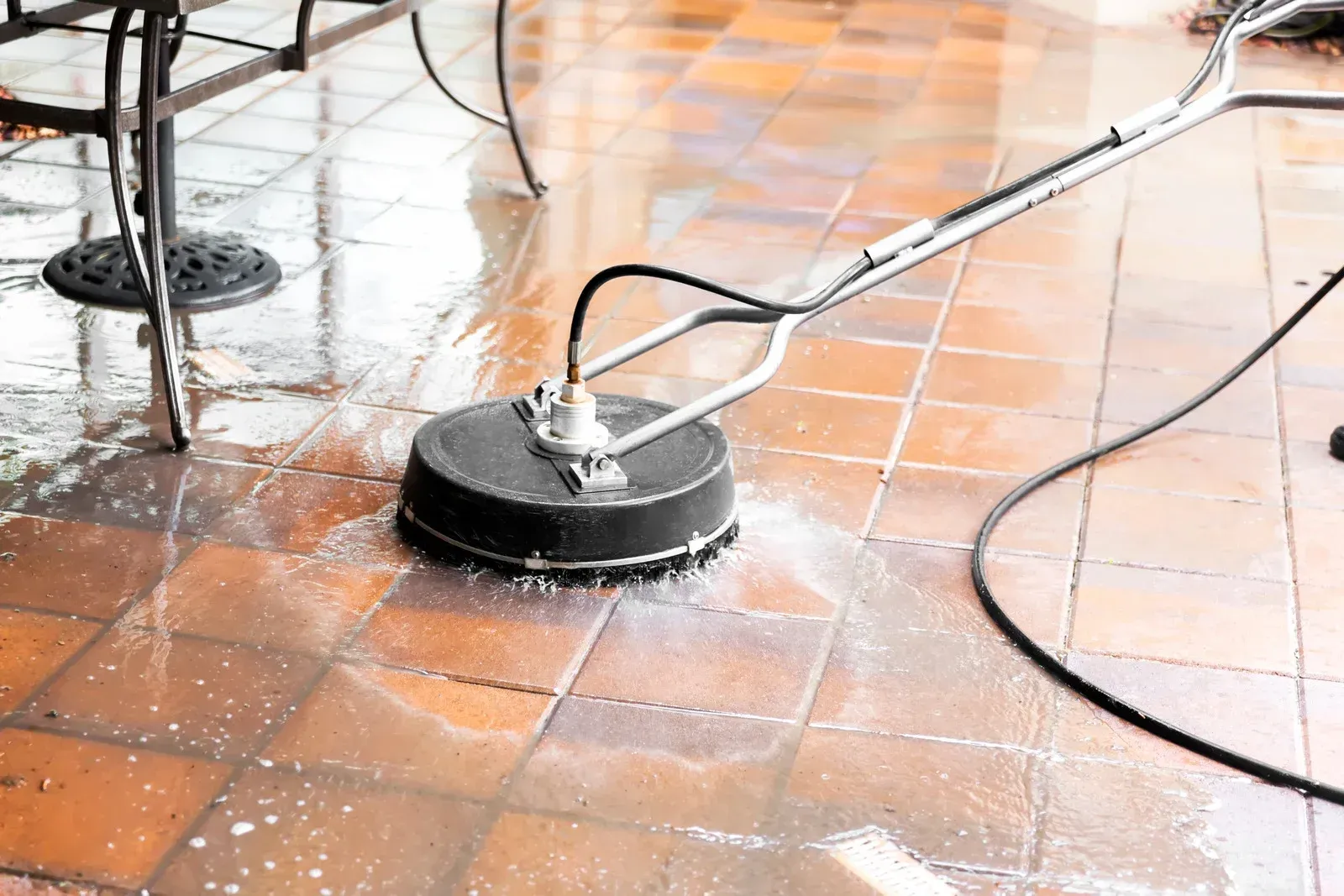 A person is cleaning a tiled floor with a machine.