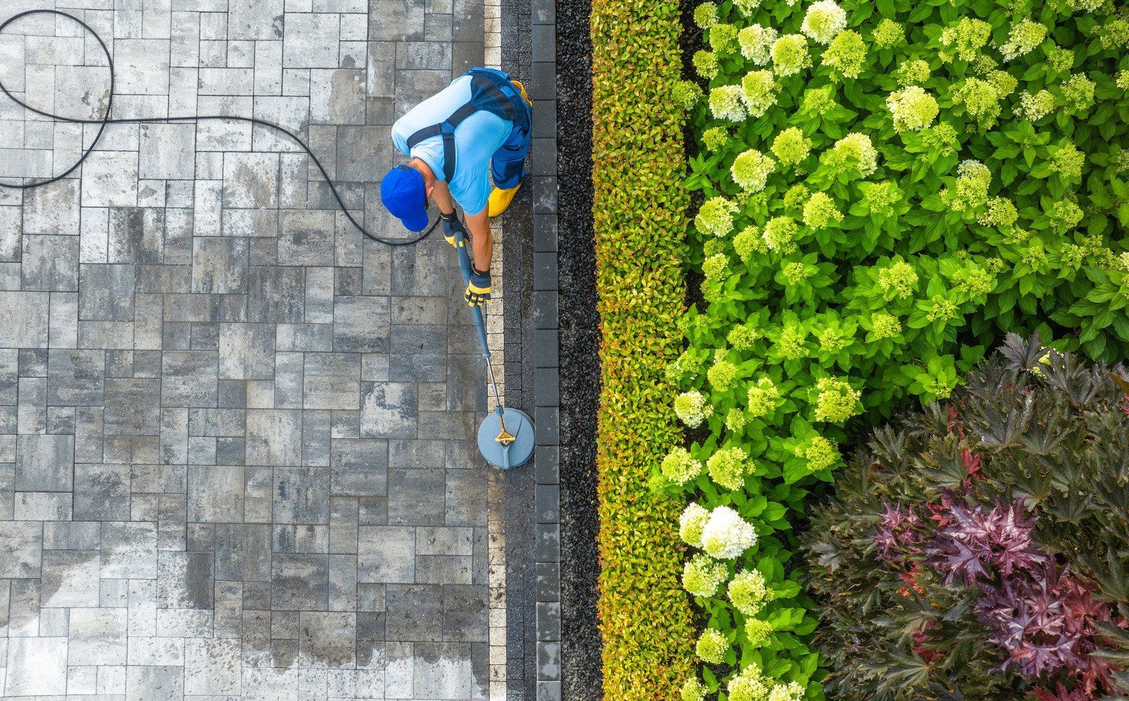 A man is cleaning a wooden deck with a high pressure washer.