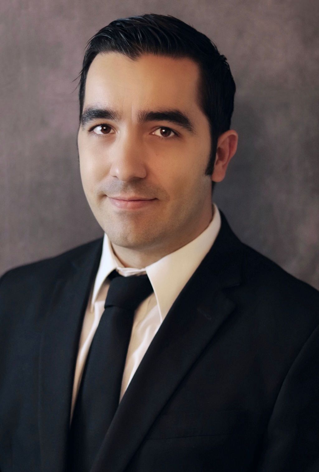 A man in a suit and tie is smiling for the camera