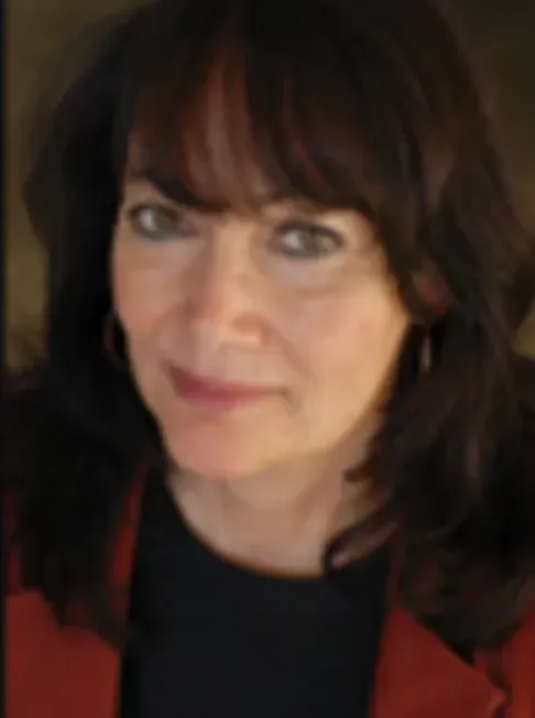 A man in a grey shirt is smiling for the camera