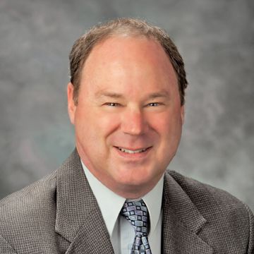 A man in a suit and tie is smiling for the camera.