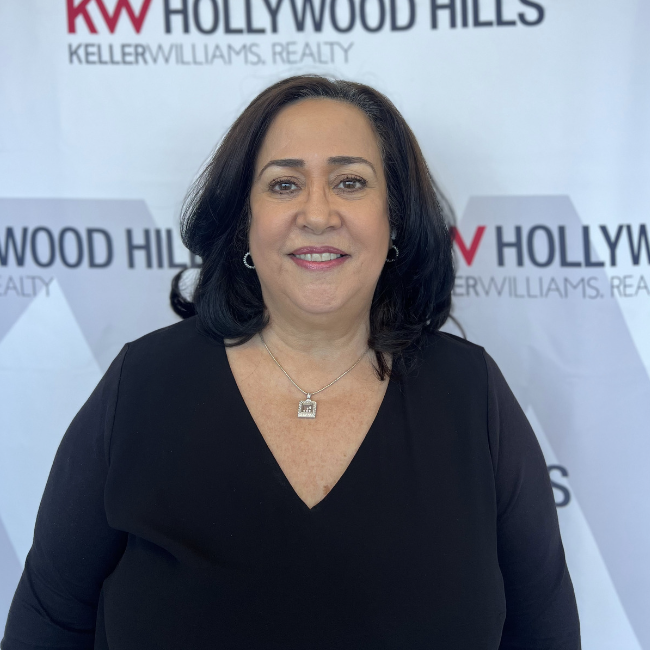 A woman stands in front of a sign that says hollywood hills