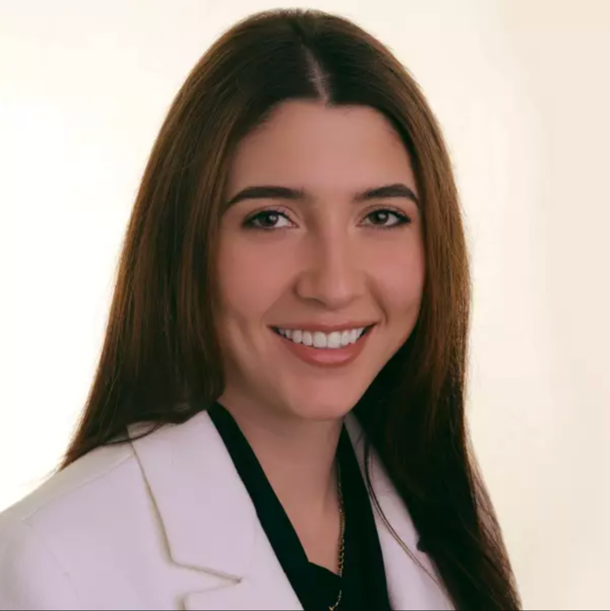 A woman in a white lab coat is smiling for the camera