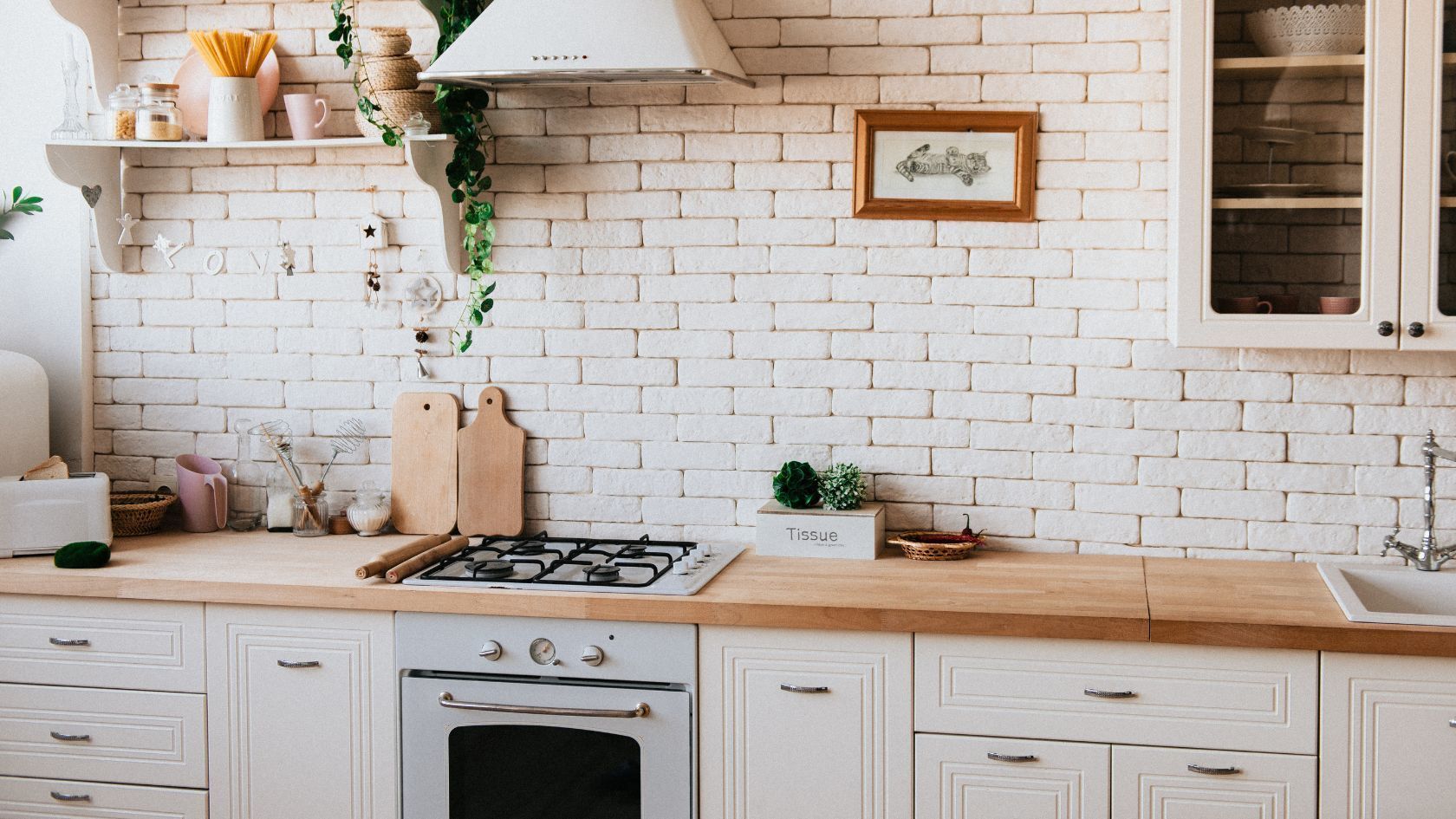 White kitchen with brick backsplash, wooden countertops, and white cabinets.