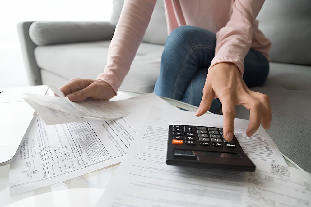 A Woman is Sitting on a Couch Using a Calculator to Calculate Her Bills — Eacham Accounting and Audits in Malanda, QLD