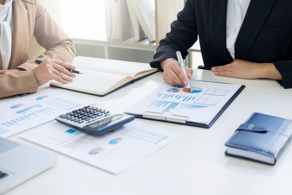 Two Women Are Sitting at a Table With a Calculator and Papers — Eacham Accounting and Audits in Malanda, QLD