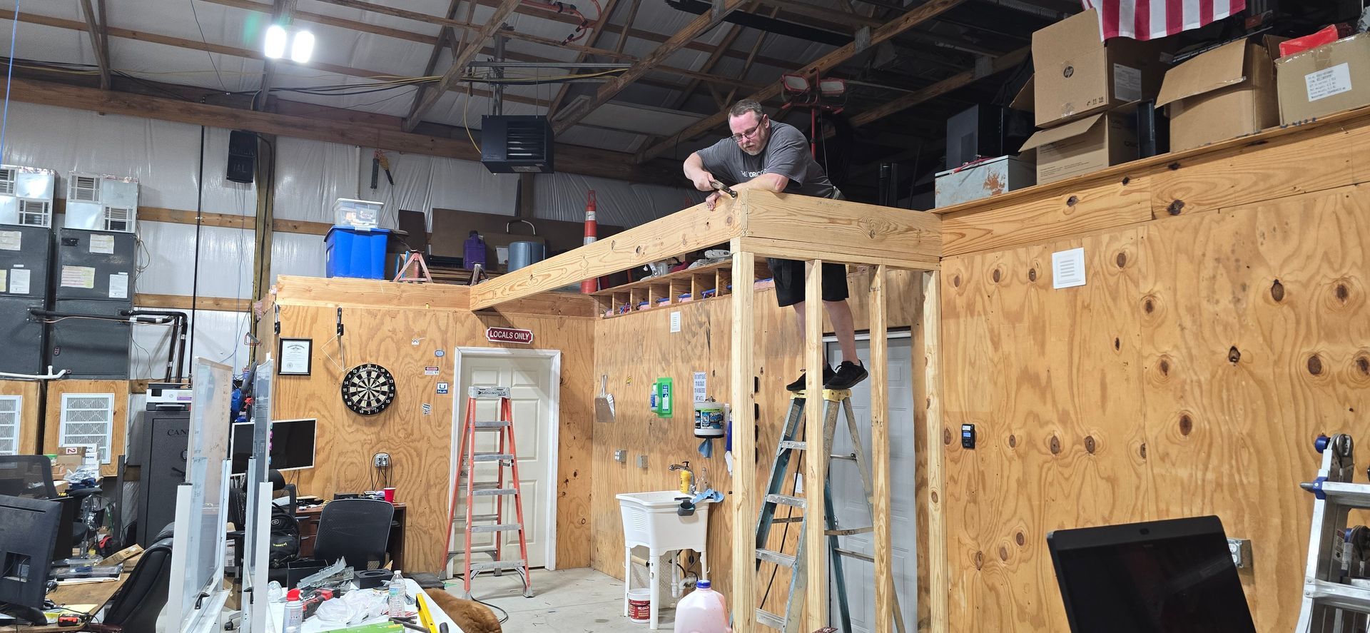 A view inside a barn or garage featuring an elevated wooden loft with a horizontal slat railing above a workspace.