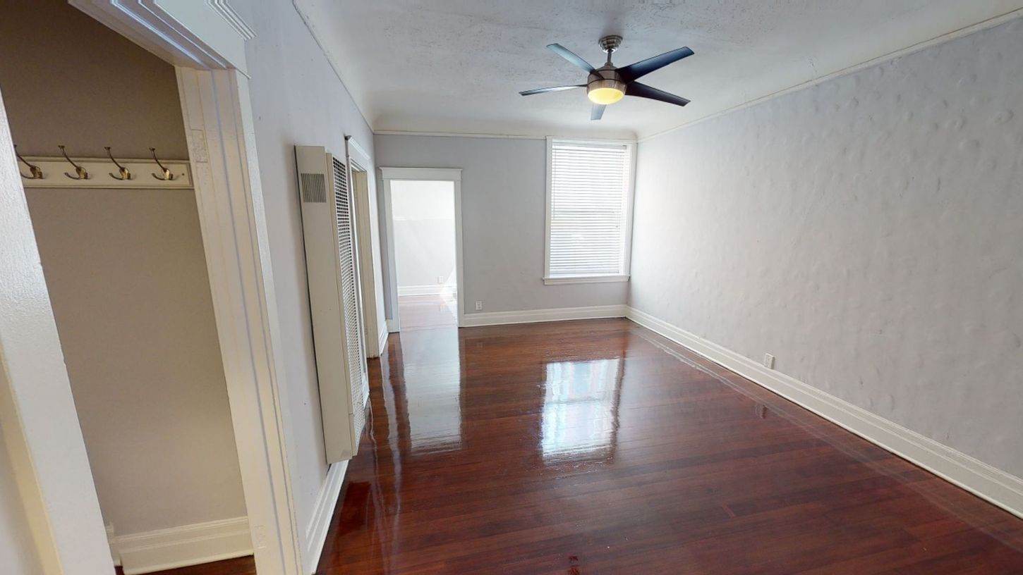 Empty room with hardwood floors, a ceiling fan, and a closet doorway.