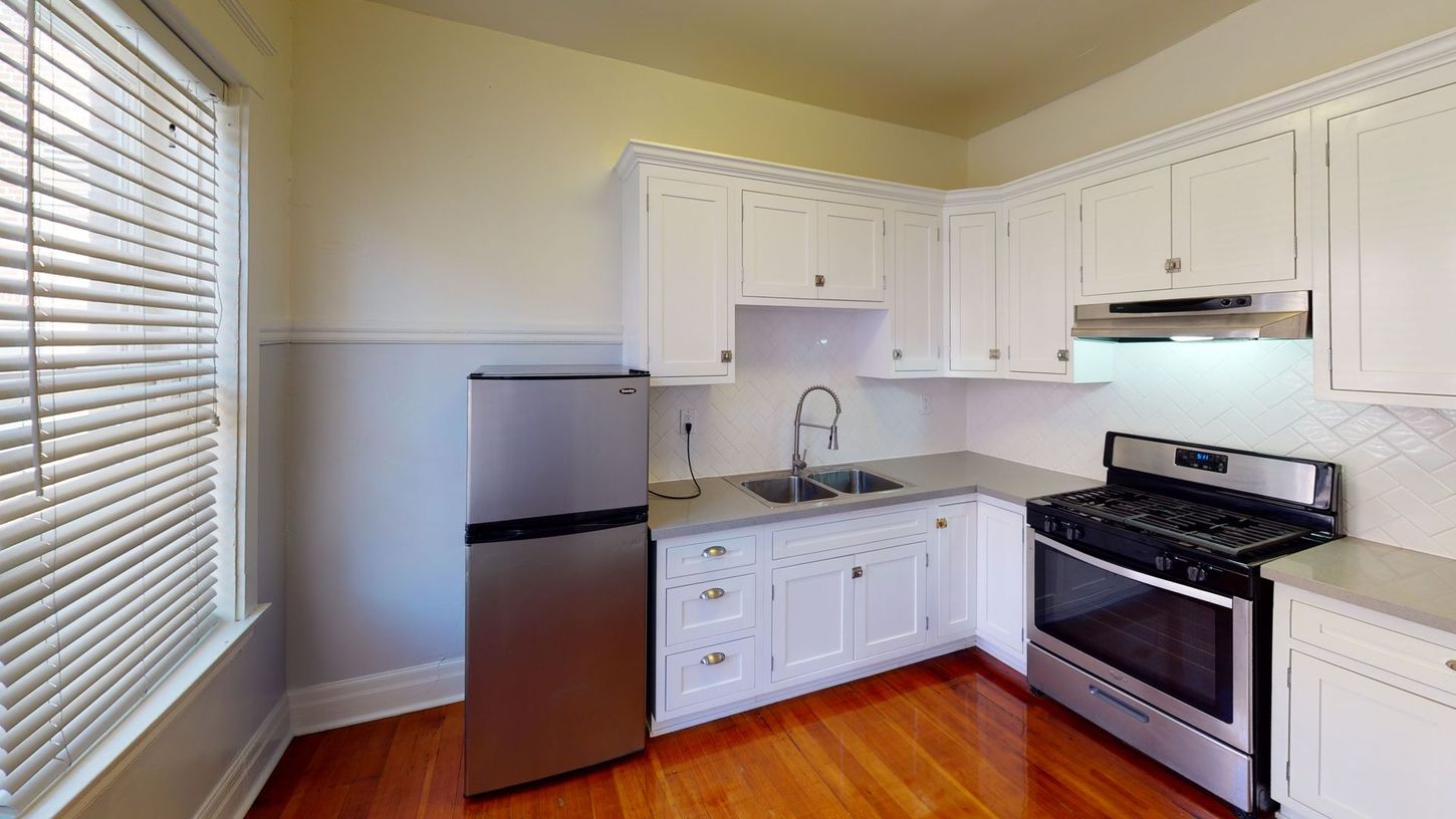 Kitchen with white cabinets, stainless steel appliances, and wood floor.
