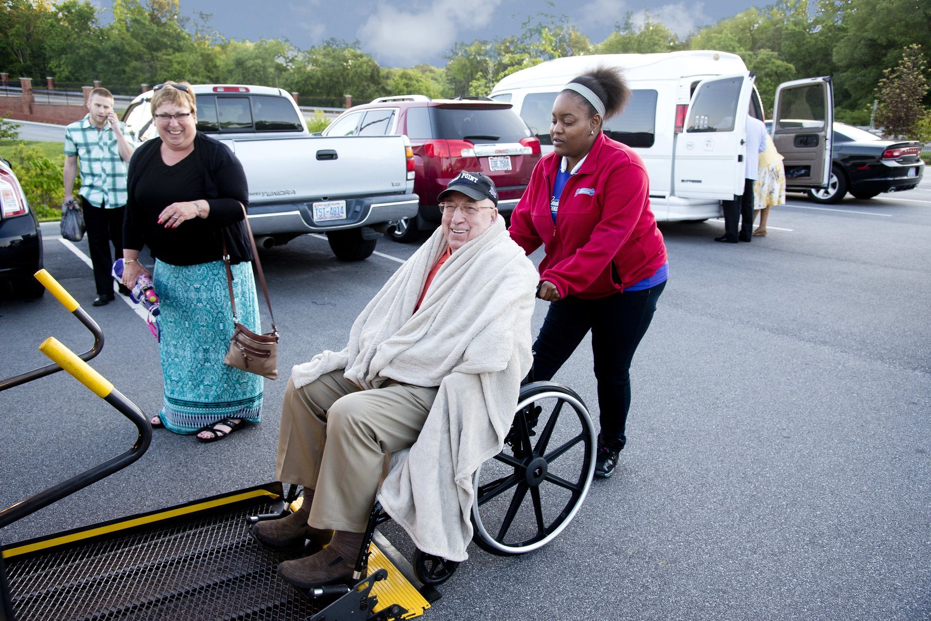 Person in wheelchair being assisted onto a ramp. 