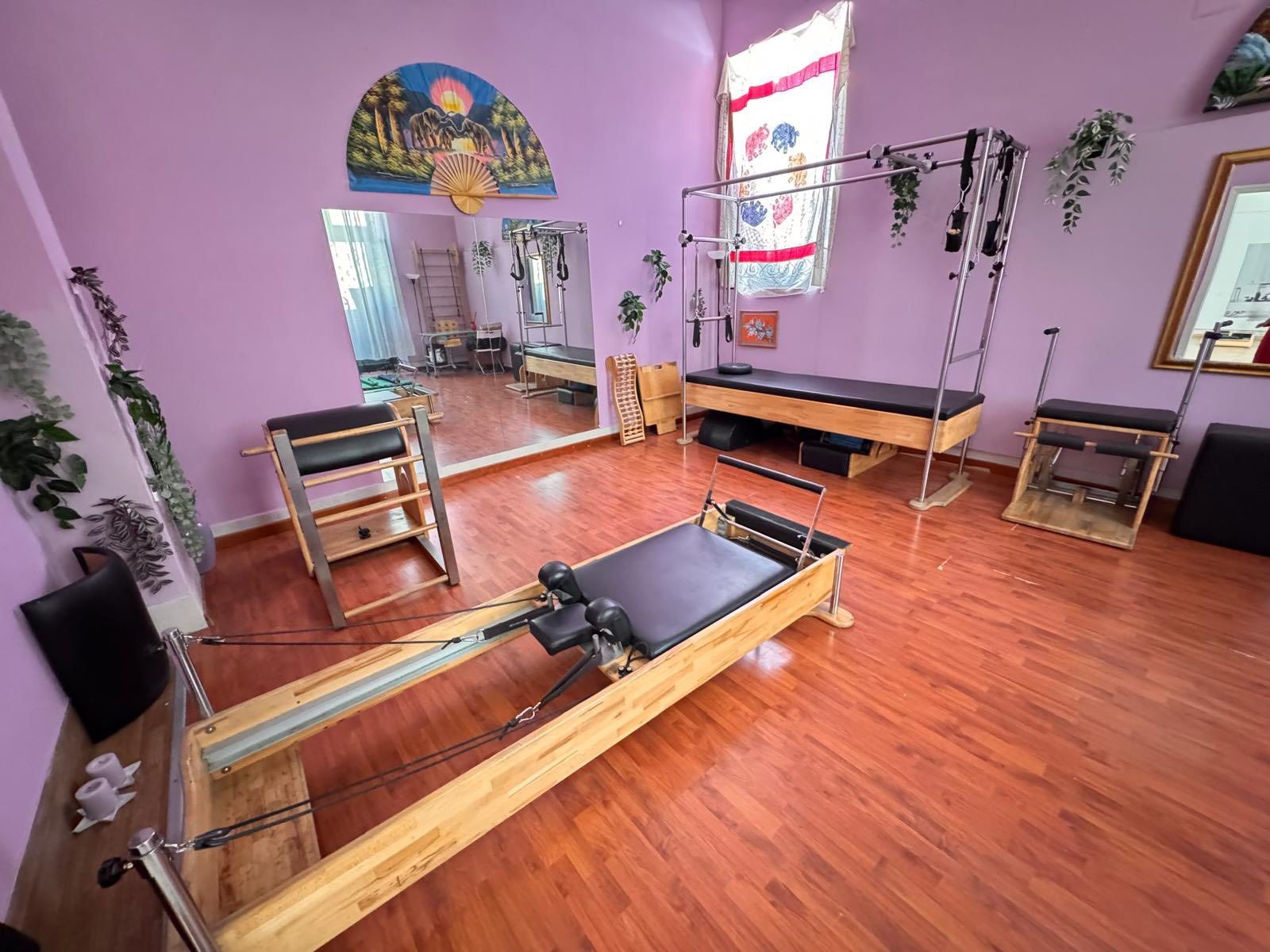 Studio Pilates: attrezzature in legno, pareti viola, specchio, pavimenti in legno.