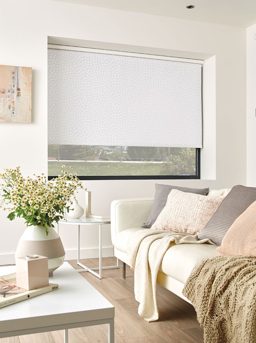 A Living Room With a Couch, Table, Vase of Flowers and a Window — Elegant Blinds & Awnings in Forster, NSW