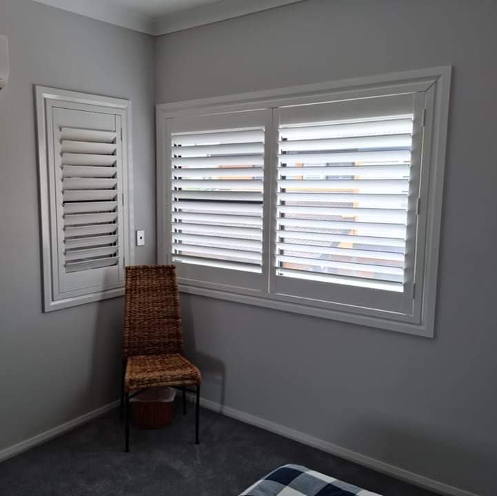 A Room With Two Windows and a Chair in the Corner — Elegant Blinds & Awnings in Forster, NSW