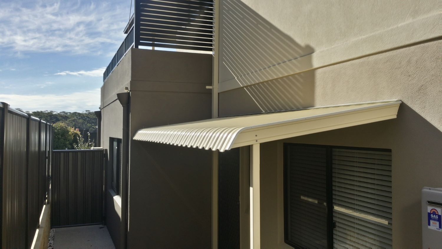 A House With a Balcony and a Canopy on the Side of It — Elegant Blinds & Awnings in Forster, NSW