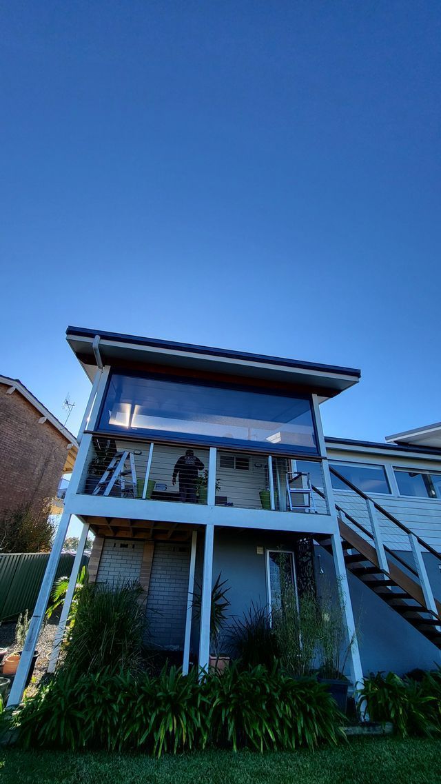 A House With a Balcony and Stairs on the Side of It — Elegant Blinds & Awnings in Forster, NSW