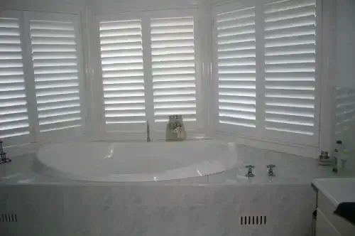 A Bathroom With a Jacuzzi Tub and White Shutters on the Windows — Elegant Blinds & Awnings in Forster, NSW