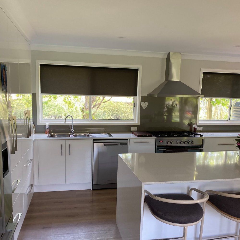 A Kitchen With White Cabinets and Stainless Steel Appliances — Elegant Blinds & Awnings in Gloucester, NSW