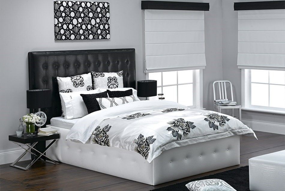 A Black and White Bedroom With a Bed and a Chair — Elegant Blinds & Awnings in Forster, NSW
