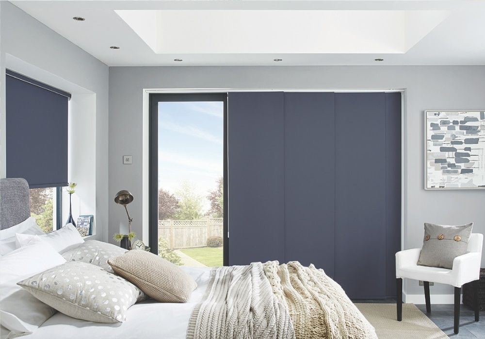A Bedroom With a Bed, Chair and Sliding Glass Doors — Elegant Blinds & Awnings in Forster, NSW