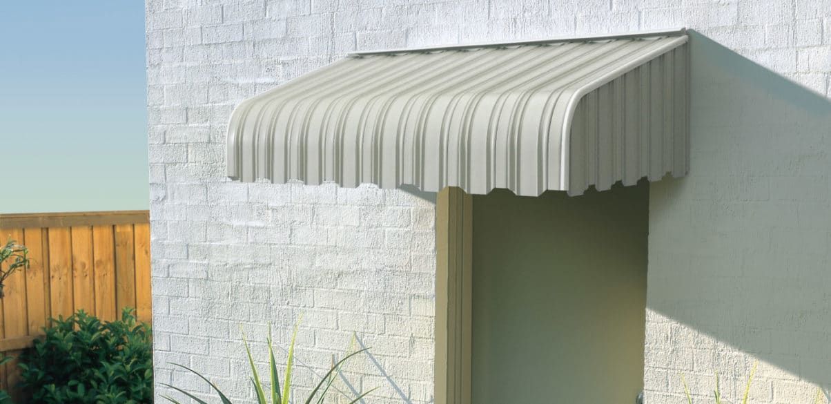 A White Awning is on the Side of a White Brick Building — Elegant Blinds & Awnings in Forster, NSW