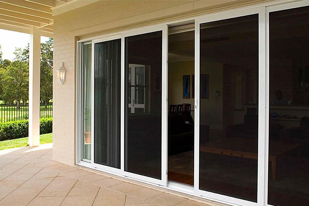 A Patio With Sliding Glass Doors Leading to a Living Room — Elegant Blinds & Awnings in Forster, NSW