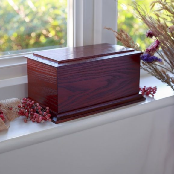 Wooden urn on a windowsill, with flowers.