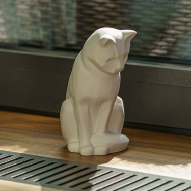 White ceramic cat statue sitting on wooden surface.