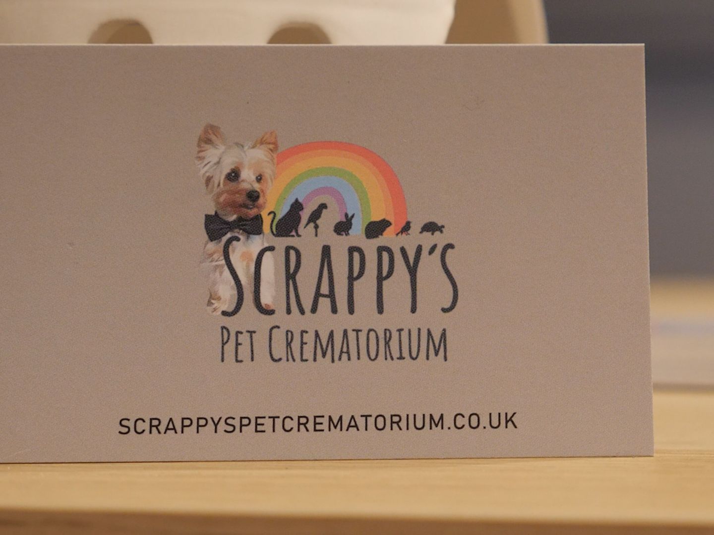 Logo of Scrappy's Pet Crematorium featuring a dog with a rainbow and silhouettes of animals.