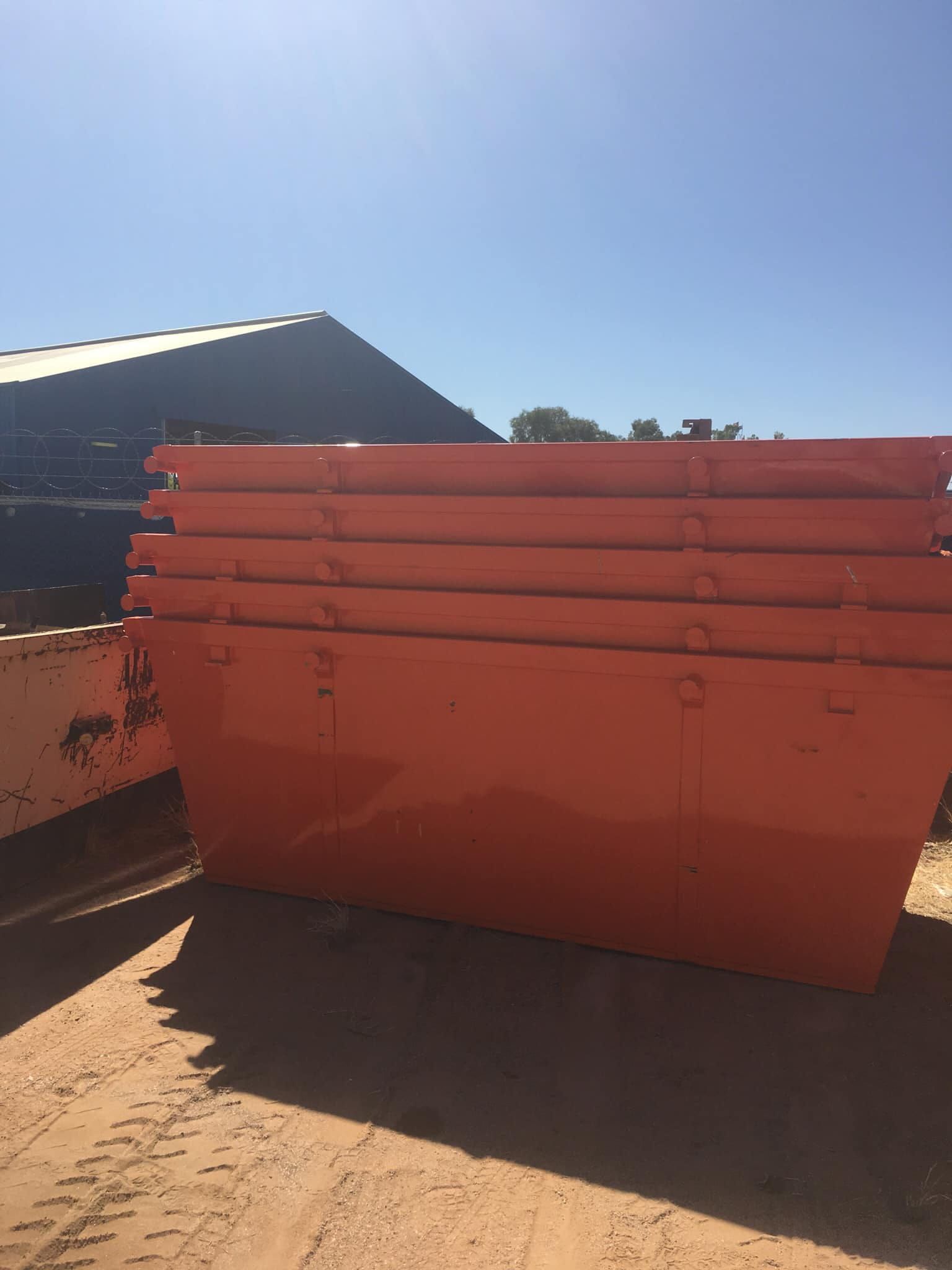 A Stack of Four Bright Orange Metal Dumpsters Sitting on Dirt — Alice Skip Hire in Alice Springs, NT