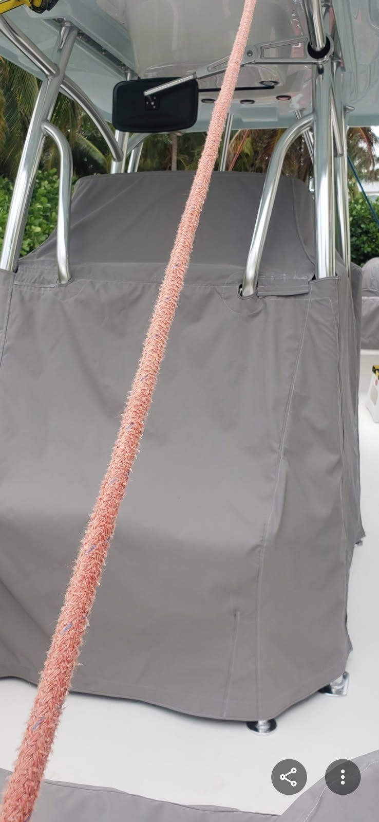 Gray mobility seat with a red rope strap inside a metal-framed outdoor canopy or cart.