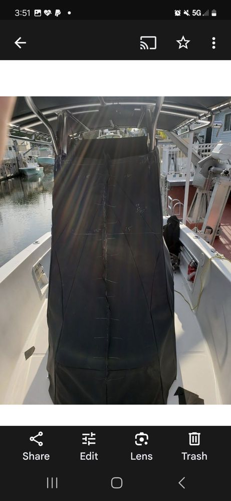 A center console on a boat, covered by a black protective canvas, positioned on the deck at a marina.