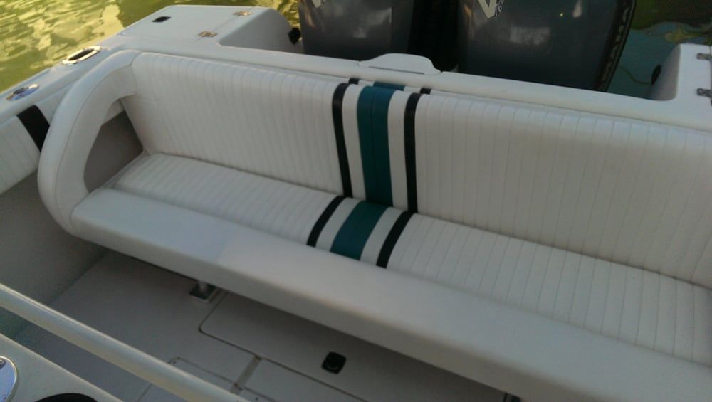 A white bench seat on a boat deck, featuring a centered teal and black striped accent panel.