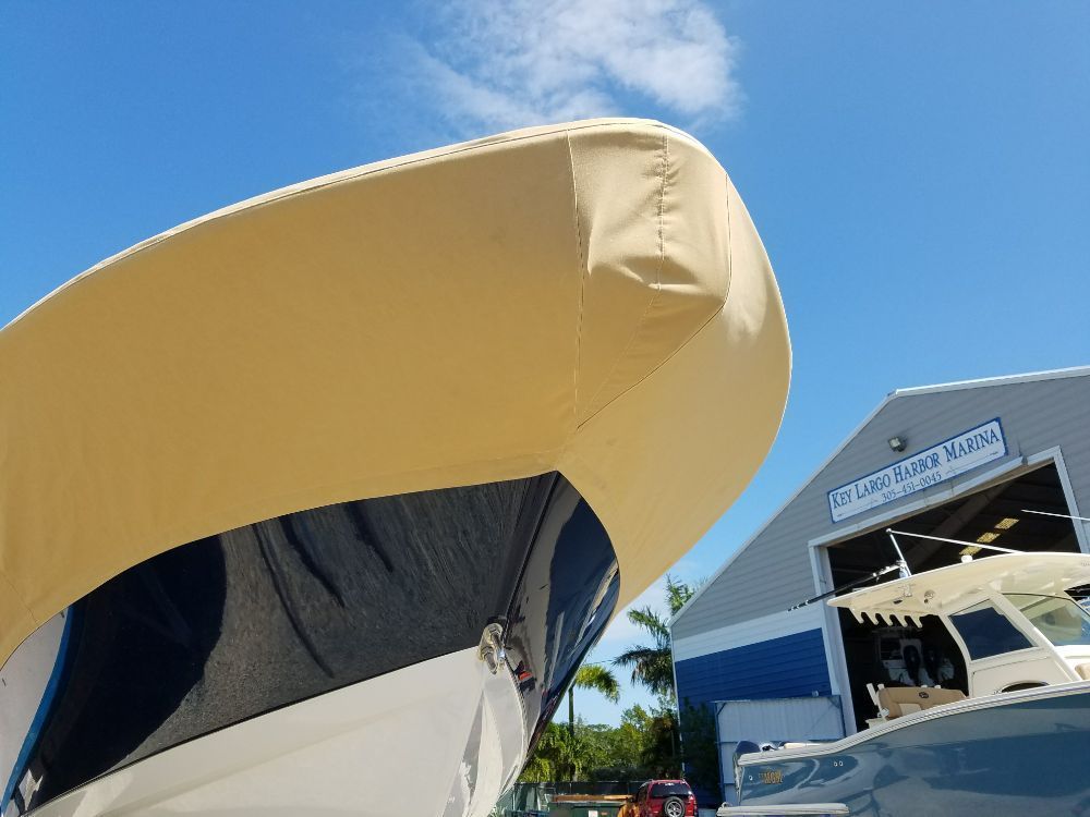 A boat covered with a tan tarp parked outside a building marked Lake Island Marina.
