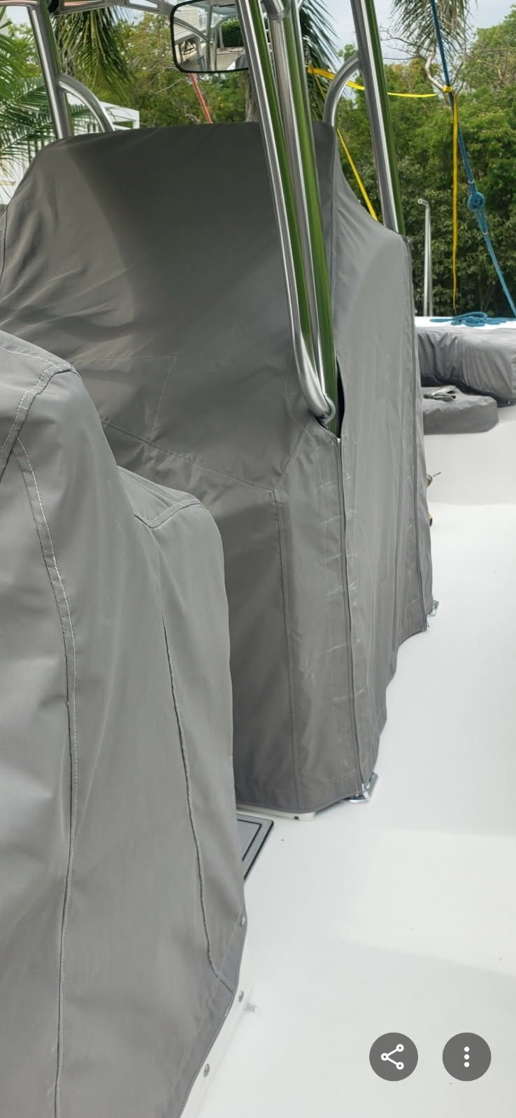 Gray covered outdoor lounge chairs lined up beside a pool with palm trees in the background