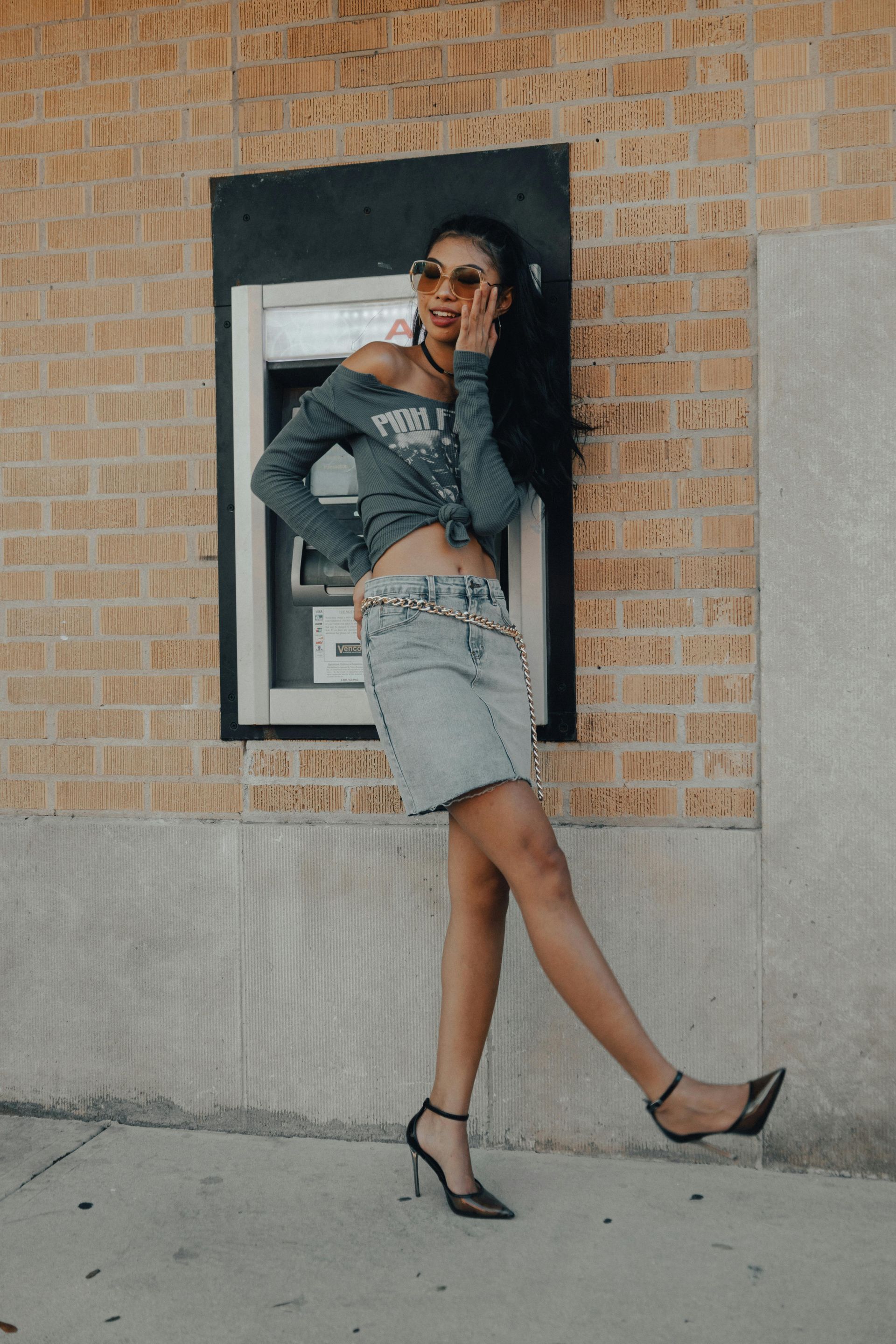 A woman is standing next to an atm machine talking on a cell phone.
