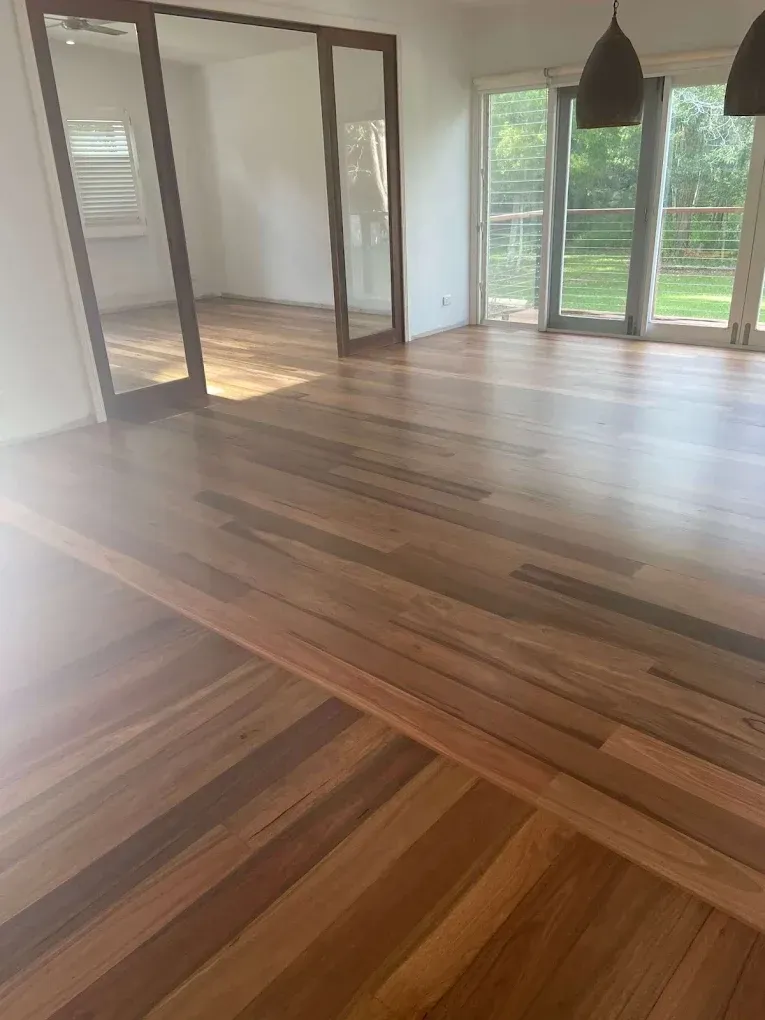 An Empty Room With Hardwood Floors and a Yellow Light — Tweed Coast Cork & Timber Floors In Tweed Heads, NSW
