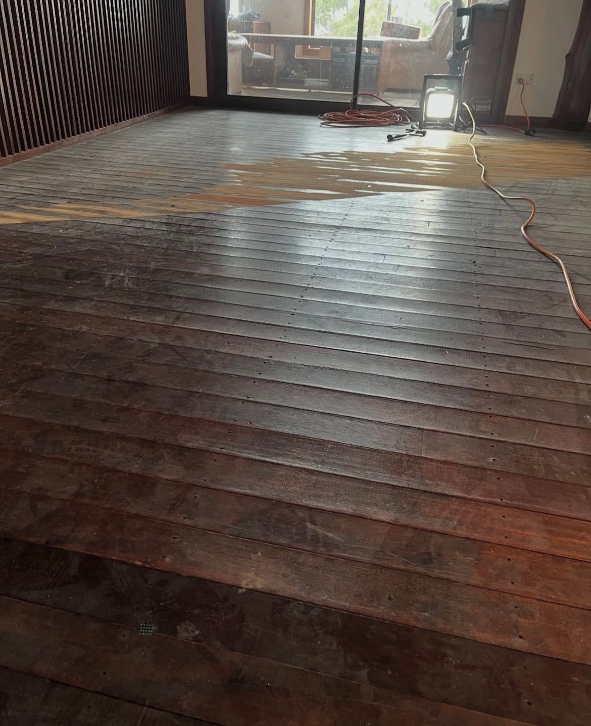 Dark wood floor partially refinished, with brown stain and work light, in a room. — Tweed Coast Cork & Timber Floors In Tweed Heads, NSW