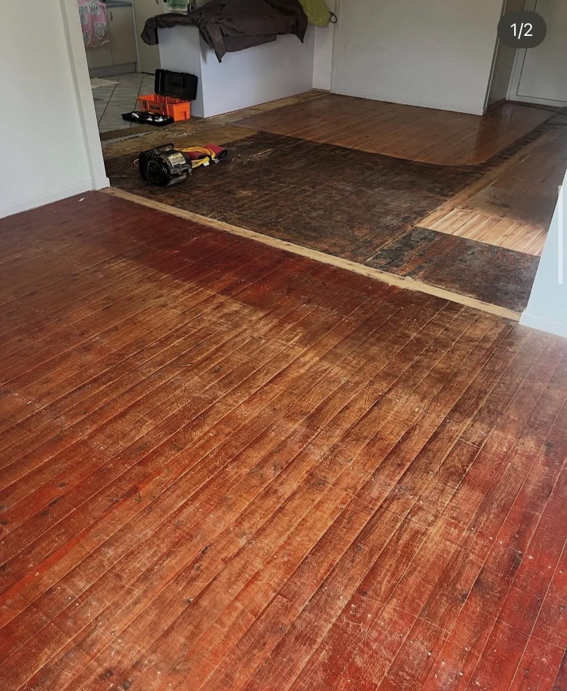 Wood floor being refinished, with a section sanded and showing raw wood, inside a home. — Tweed Coast Cork & Timber Floors In Tweed Heads, NSW