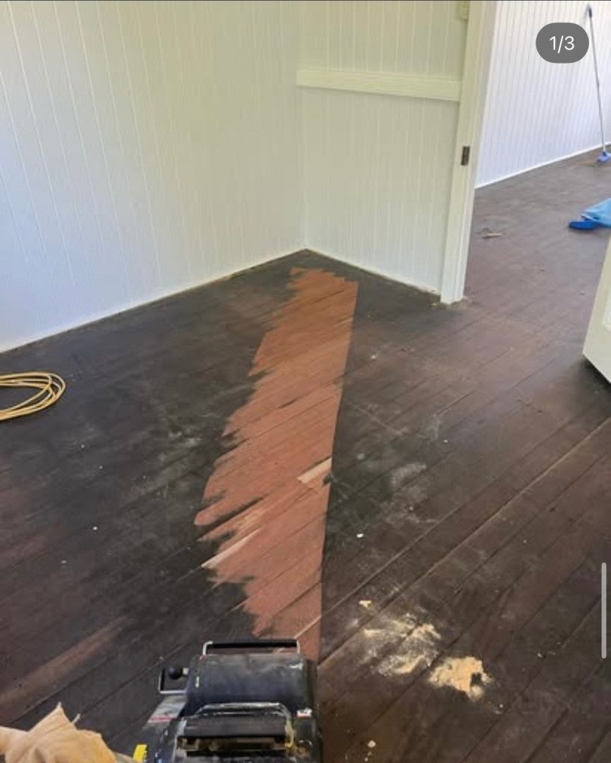 Floor being sanded with a machine, revealing a lighter wood colour. Room corner with white walls and trim. — Tweed Coast Cork & Timber Floors In Tweed Heads, NSW