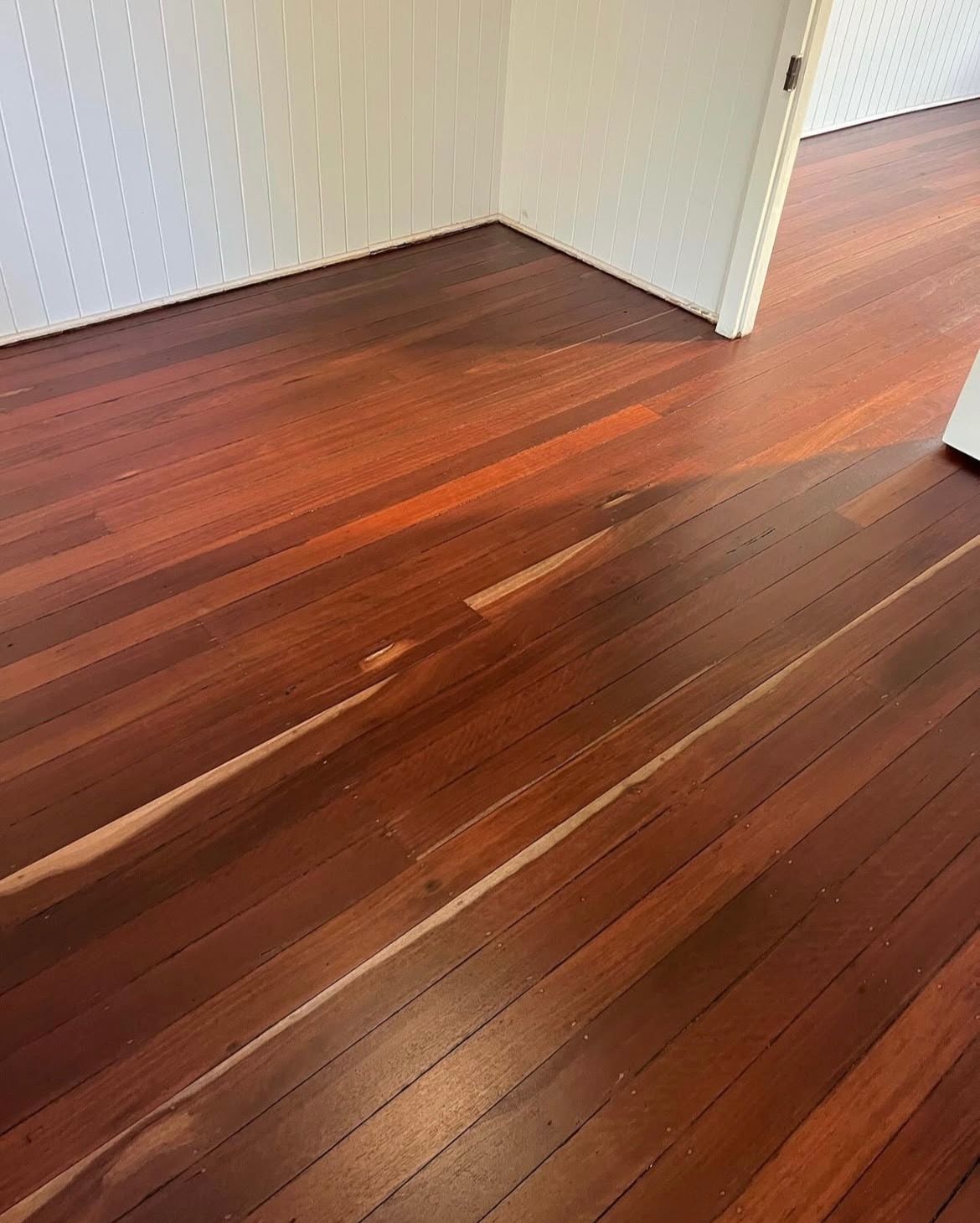 Wooden floor with light-coloured wood separating some boards, inside a room with a white door and wall. — Tweed Coast Cork & Timber Floors In Tweed Heads, NSW