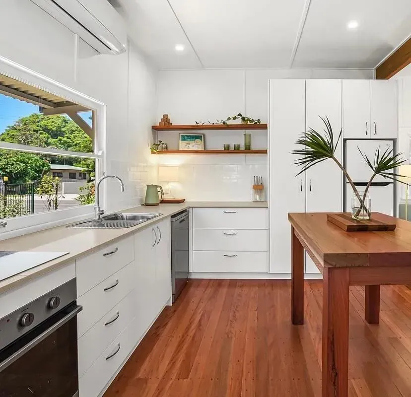 A Kitchen With White Cabinets and Hardwood Floors and a Wooden Table — Tweed Coast Cork & Timber Floors In Tweed Heads, NSW