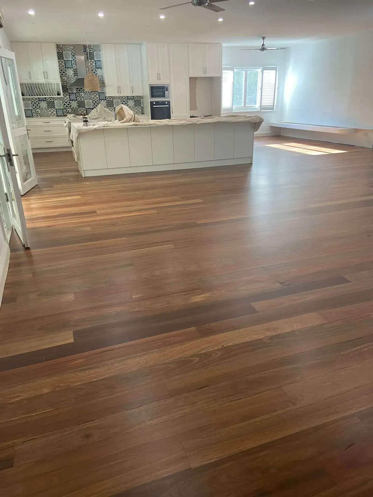 A Large Empty Room With a Wooden Floor and a Kitchen — Tweed Coast Cork & Timber Floors In Tweed Heads, NSW