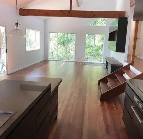 A Large Empty Room With Hardwood Floors and Stairs — Tweed Coast Cork & Timber Floors In Tweed Heads, NSW