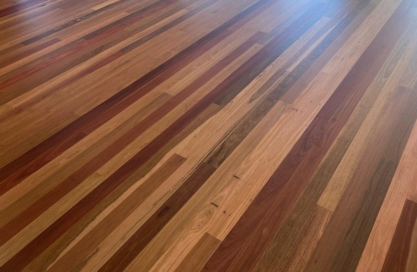 An Empty Room With Hardwood Floors and a Yellow Light — Tweed Coast Cork & Timber Floors In Tweed Heads, NSW